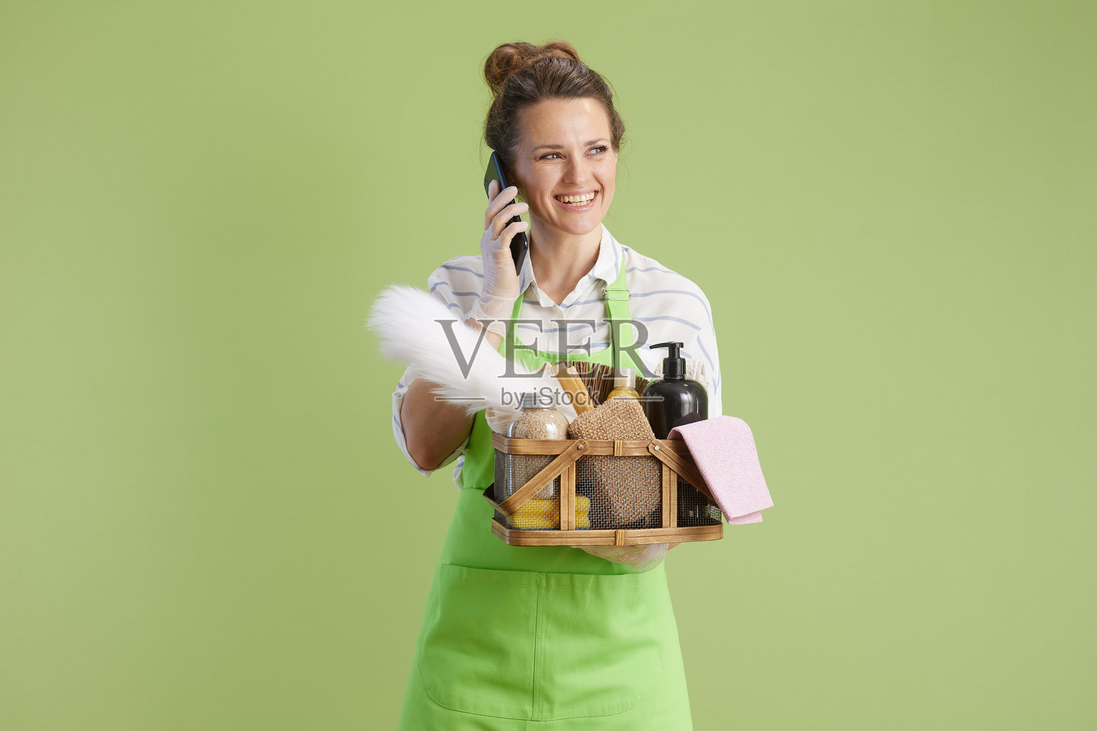 微笑的女性在绿色背景下使用智能手机通话照片摄影图片