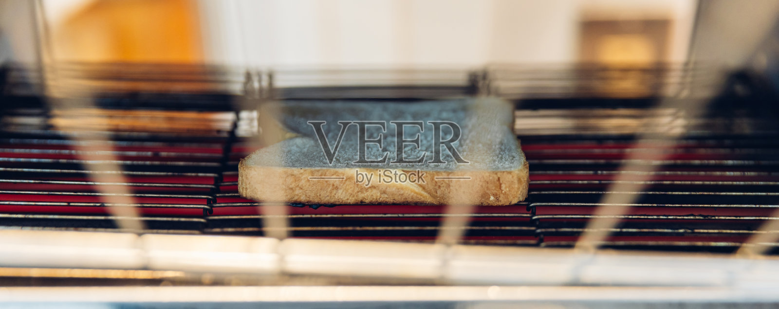 酒店中电动传送带烤面包机正在加热烤制面包。一条面包放在烤面包机中。照片摄影图片