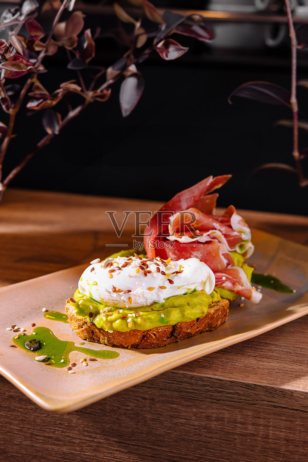 美味的烤面包，上面涂有鳄梨酱，配有水煮蛋和意大利熏火腿，摆放在木桌上照片摄影图片