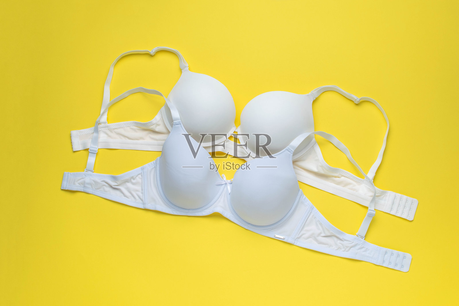 三款时尚胸罩在黄色背景上 - 极简环境中的时尚内衣展示照片摄影图片