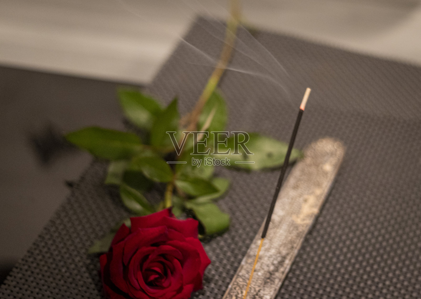 桌子上的燃烧香棒和玫瑰花的镜头。概念照片摄影图片