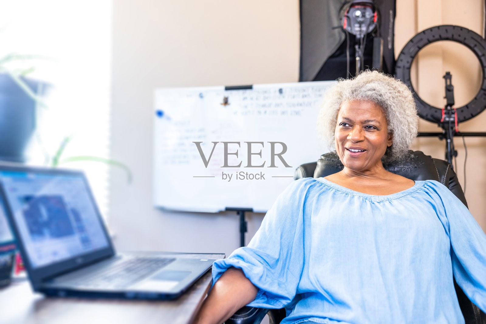 一位年长的黑人女性坐在她的家庭办公室里照片摄影图片