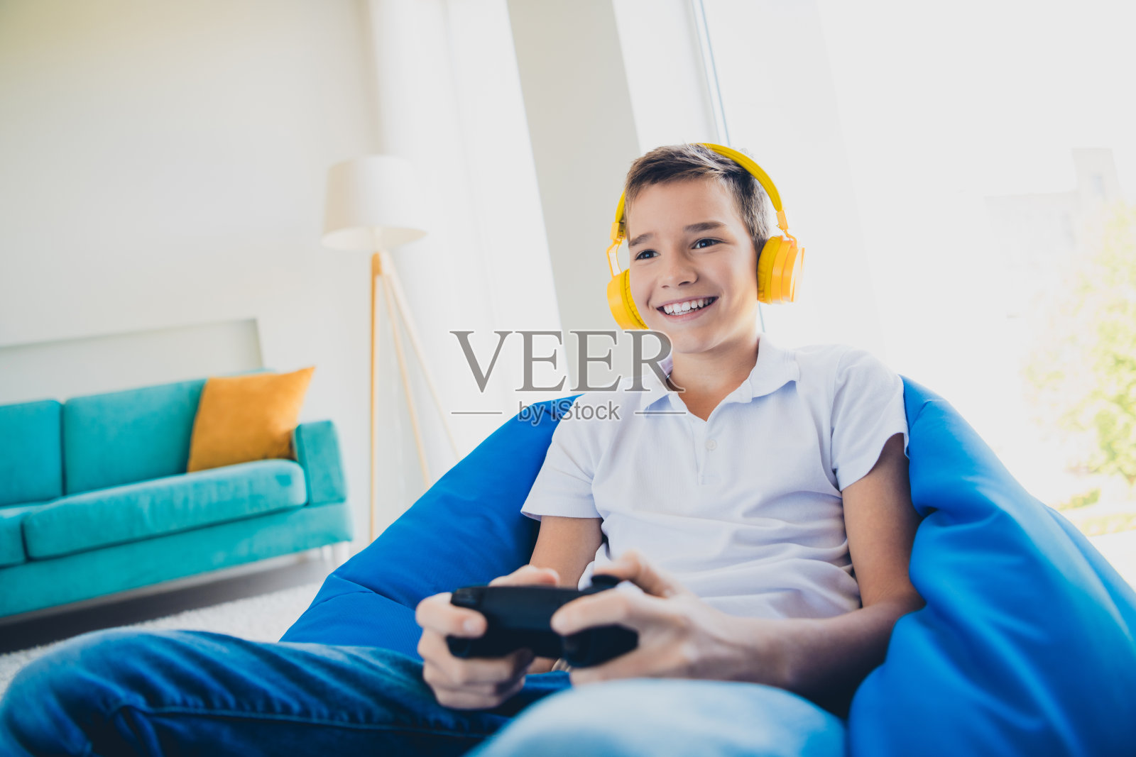 迷人的小男孩在现代室内公寓里享受玩游戏，穿着T恤。照片摄影图片