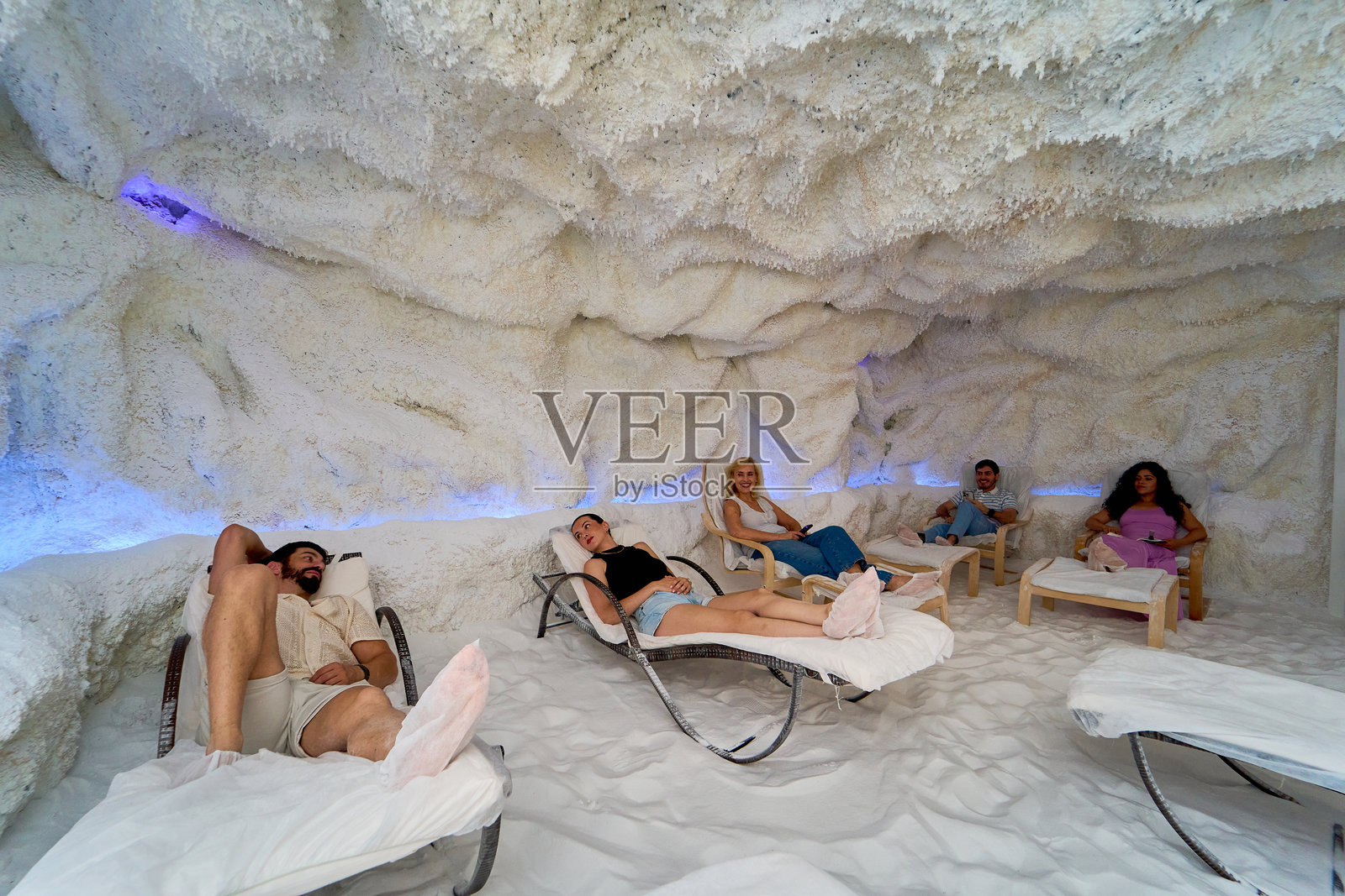 一群人在白色墙壁和蓝色灯光的房间里放松。照片摄影图片