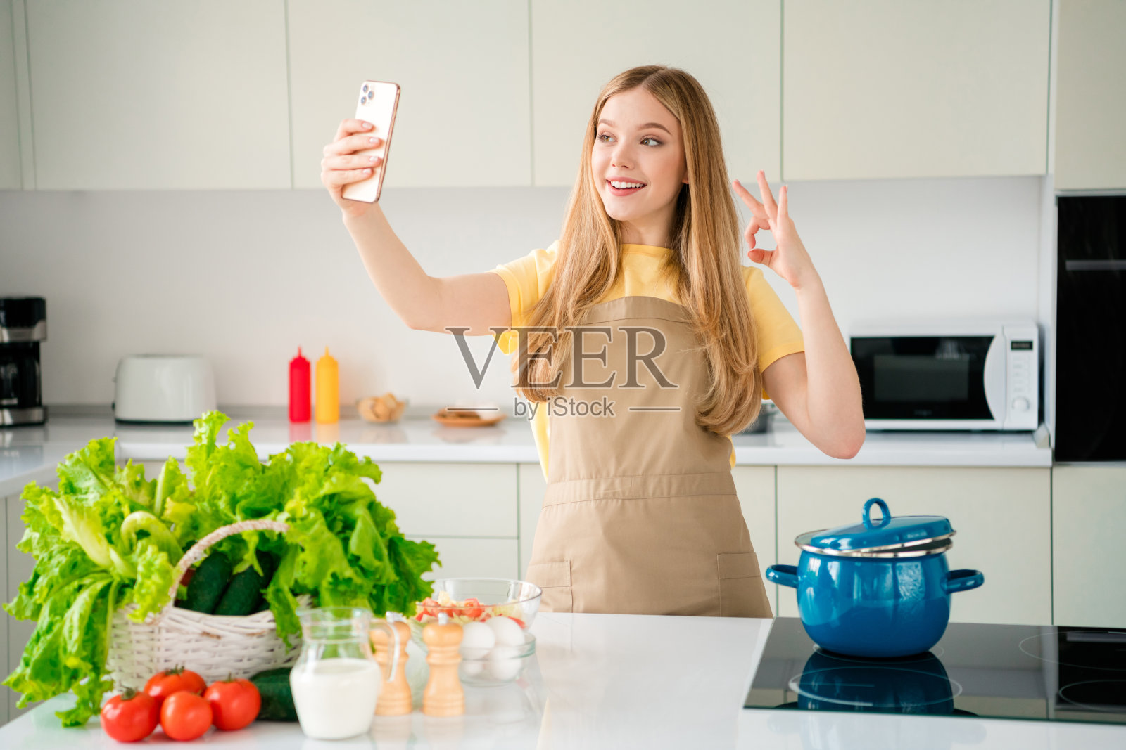 可爱的女孩在现代厨房里做午餐早餐食谱，白天的自然光照射在室内。照片摄影图片