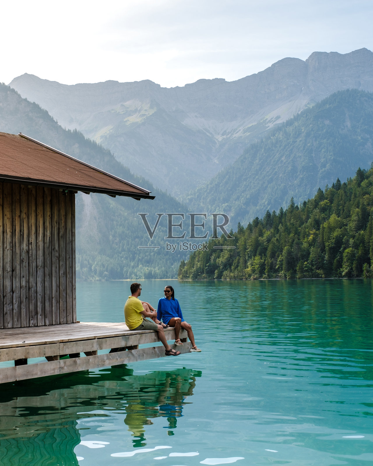 朋友们在平湖（Plansee）奥地利的宁静水面和山脉旁放松，享受令人惊叹的美景。照片摄影图片