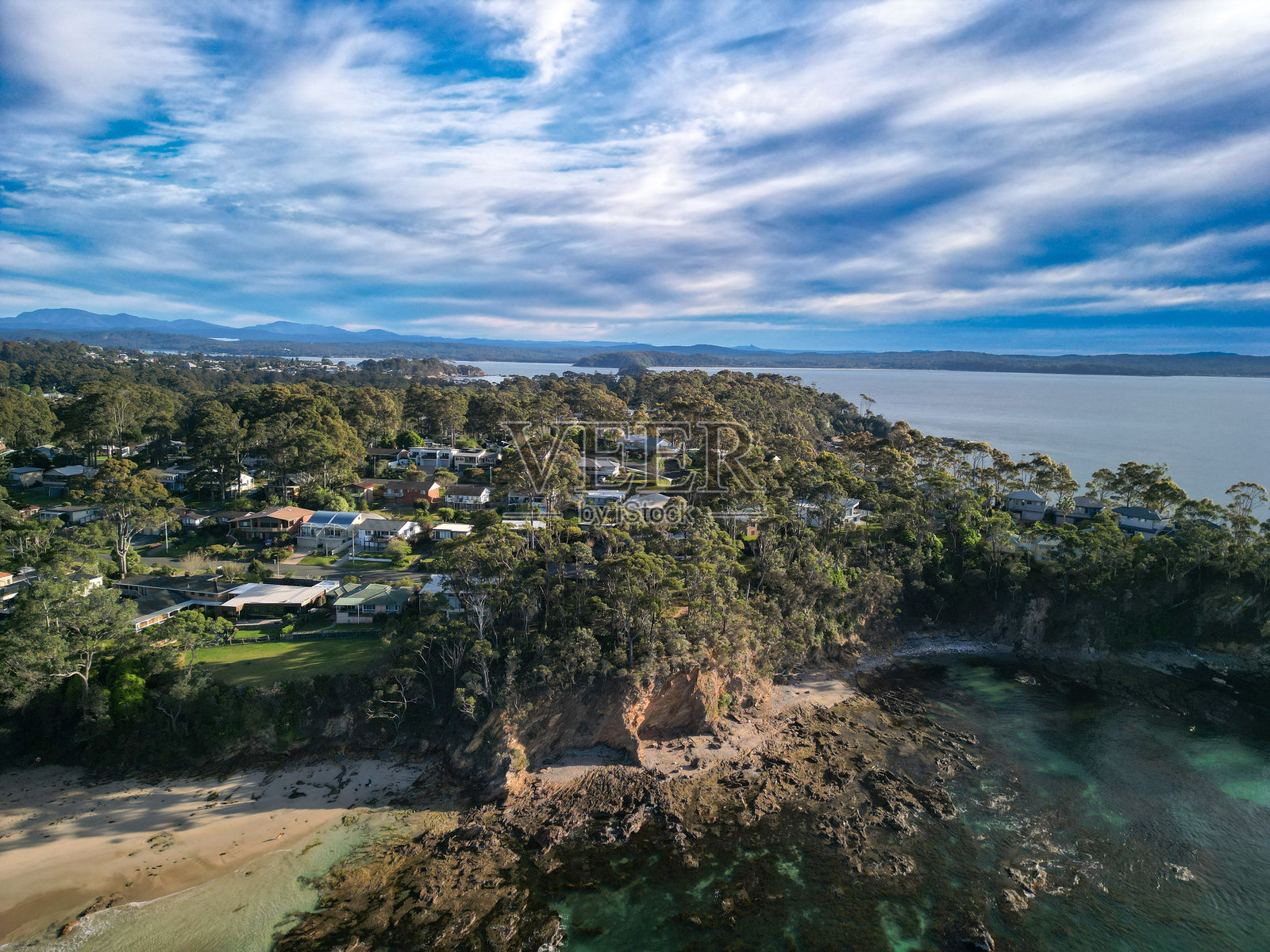 海滨小镇的鸟瞰图，绿树成荫，岩石海岸。照片摄影图片