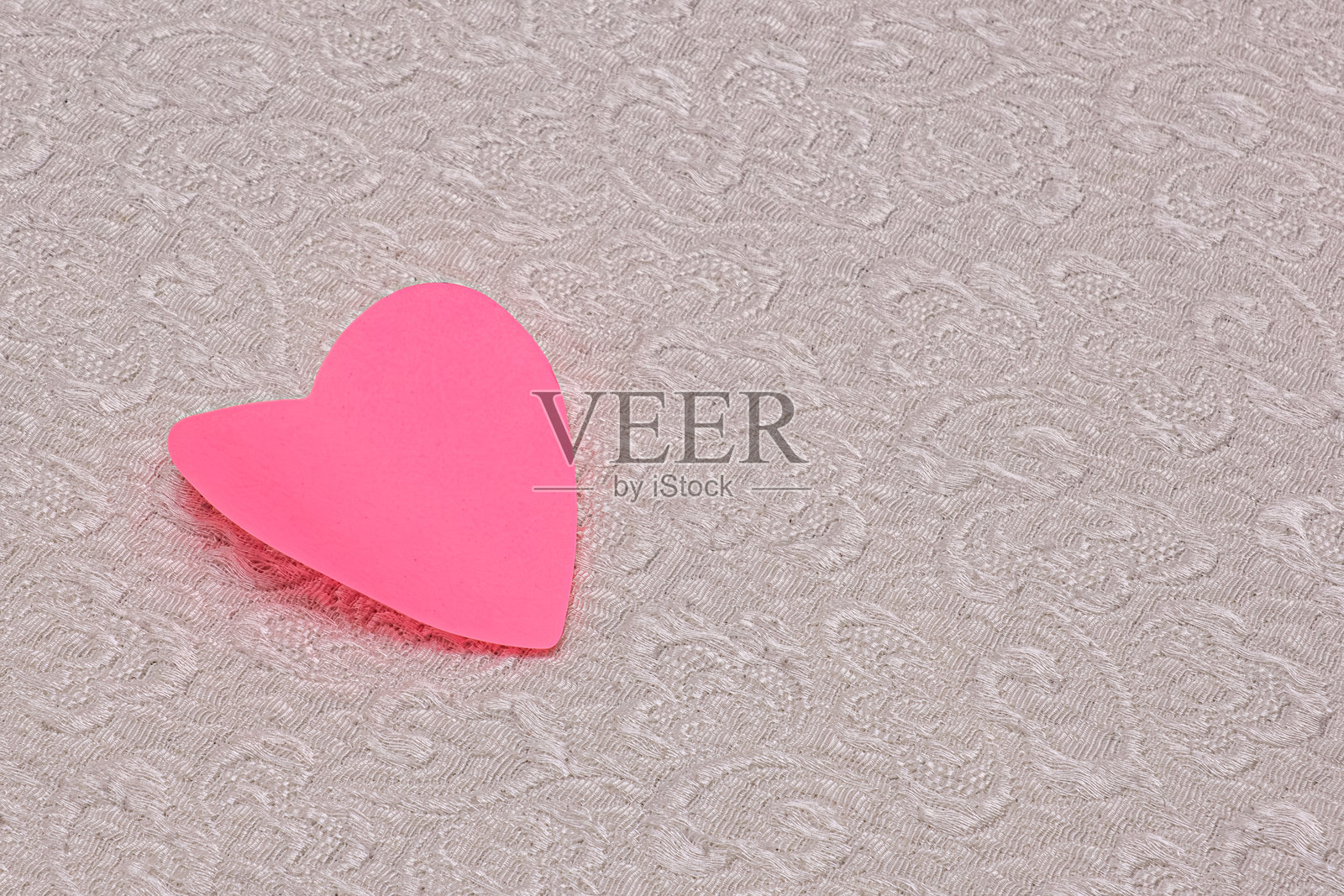 一个粉色的心形图案在白色地毯上。照片摄影图片