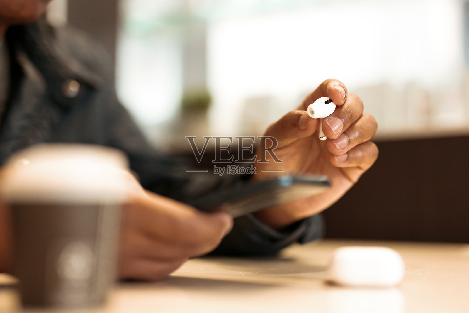 年轻男子戴着无线耳机，在咖啡馆里听音乐。照片摄影图片