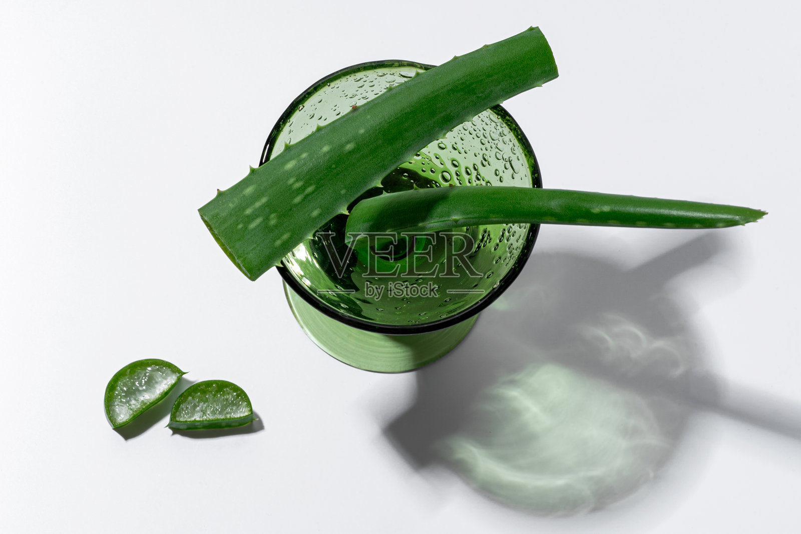 绿色玻璃杯中的芦荟茎，旁边切片，健康概念照片摄影图片