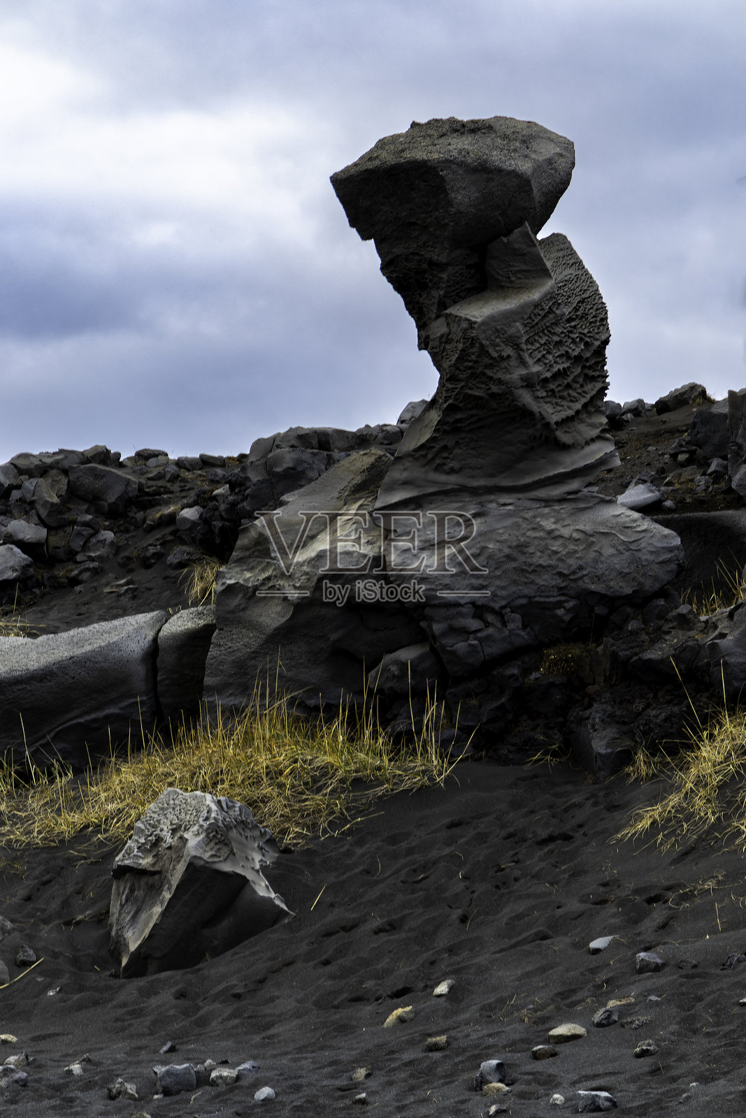 一块大石头坐落在多岩石的山坡上。火山地形照片摄影图片