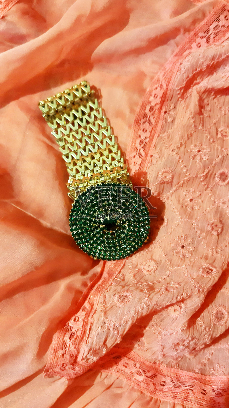 金色项链放在珊瑚色织物上。时尚背景设计，摄影。纺织品，面料模板，现代。照片摄影图片