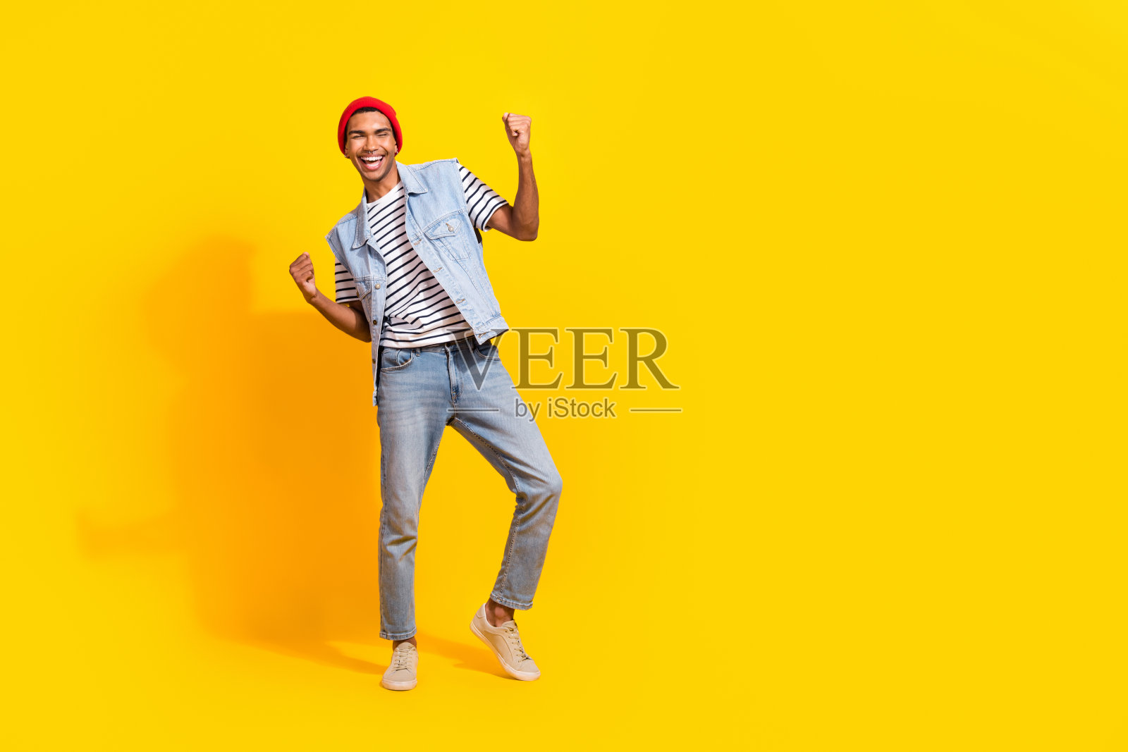 满脸欢喜的男人在黄色背景下举起拳头，庆祝好运，周围空旷。照片摄影图片