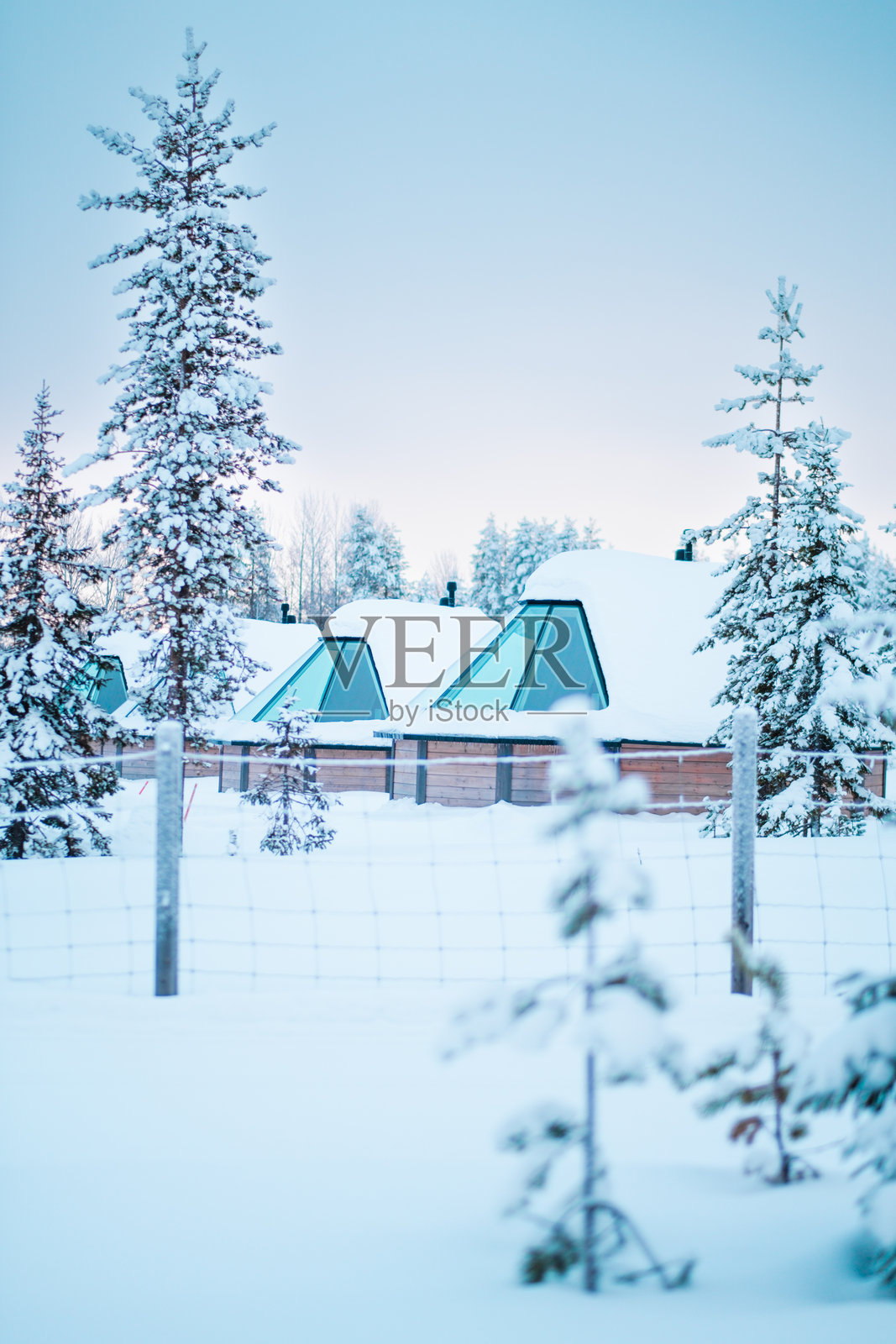 现代玻璃冰屋，设有天窗可观赏北极光，覆盖着雪。照片摄影图片