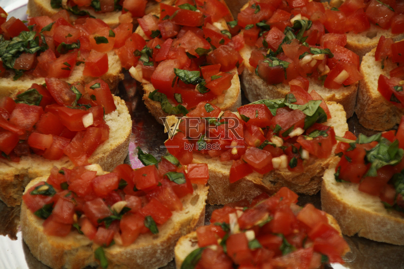 意大利面包片配法棍、西红柿、大蒜、香菜，放在银盘上。照片摄影图片