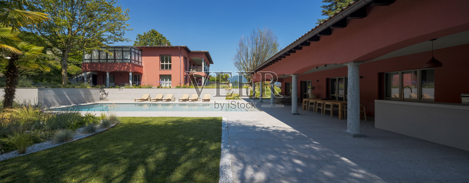 现代别墅及附属建筑的正面视图，配有游泳池、躺椅和一个大花园照片摄影图片