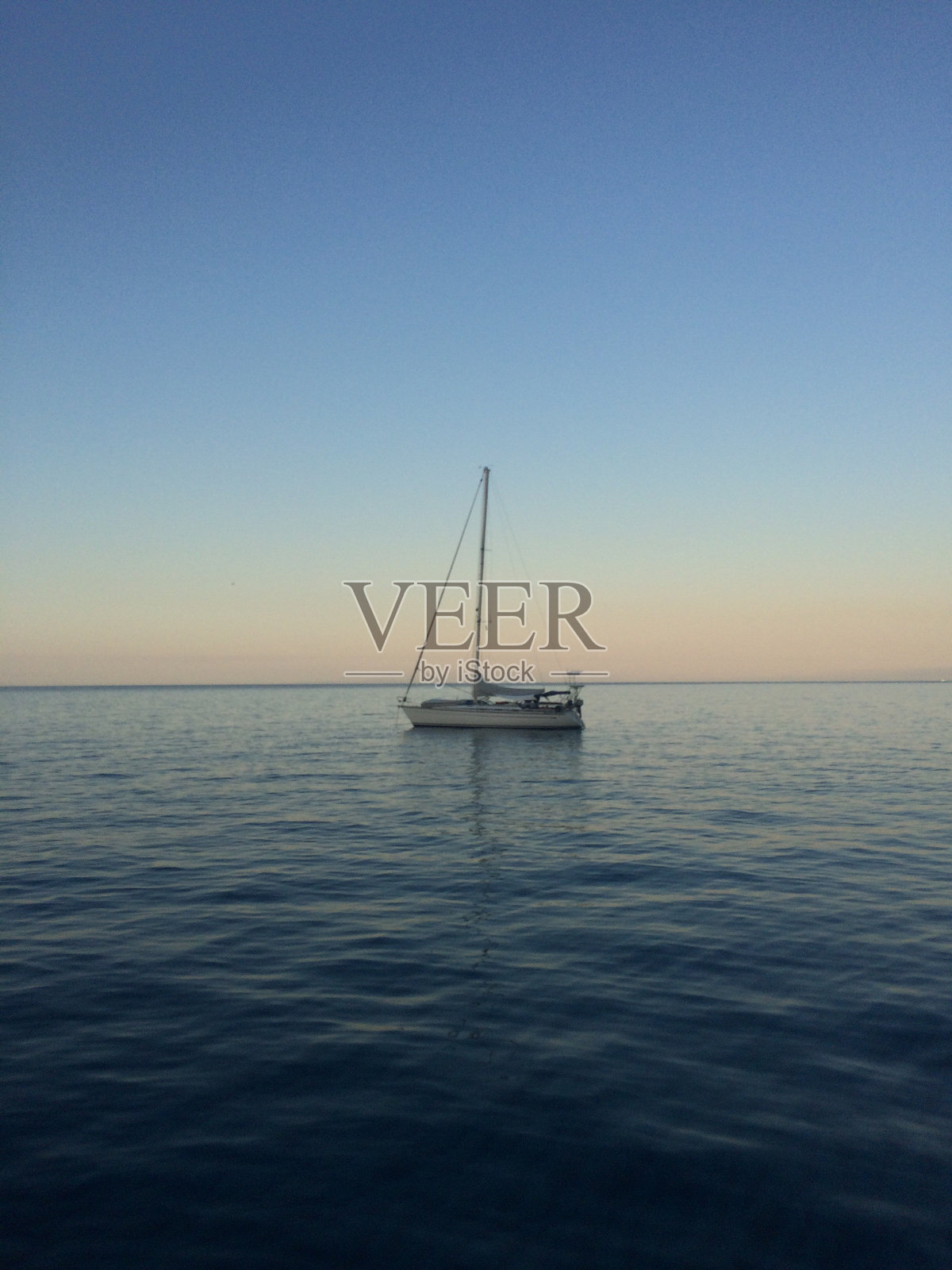 帆船在晴朗的天空下航行于海面上照片摄影图片