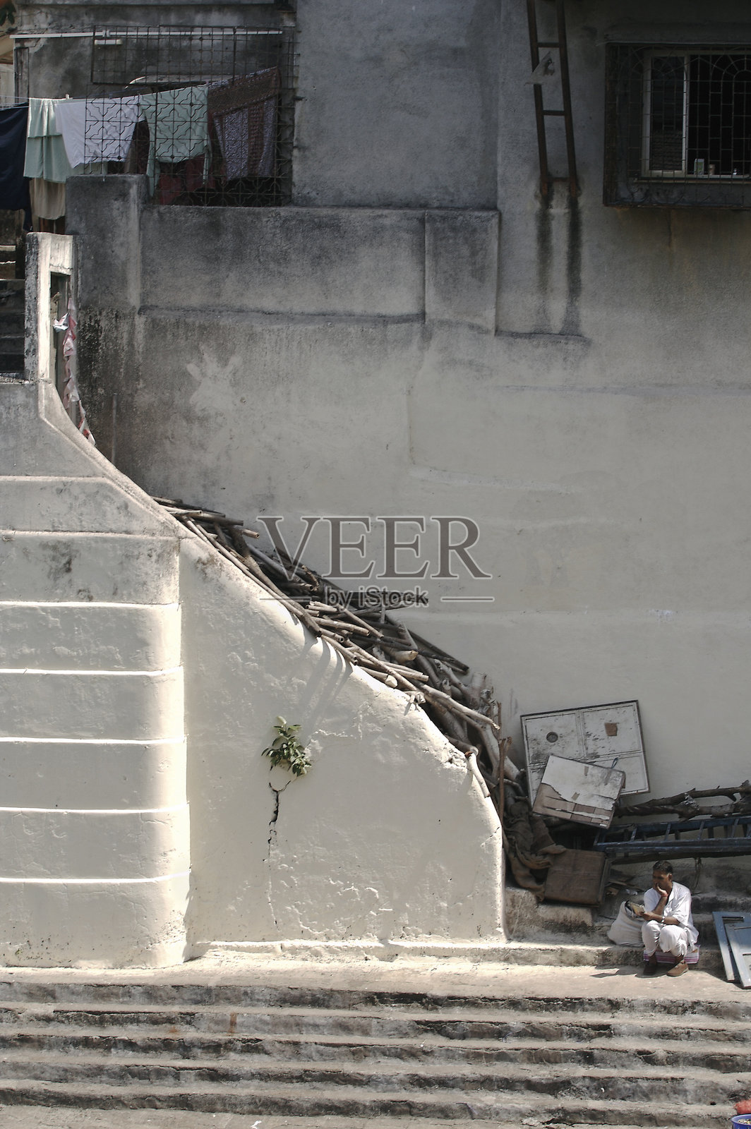 一个男人坐在台阶旁边阅读书籍的景象。照片摄影图片