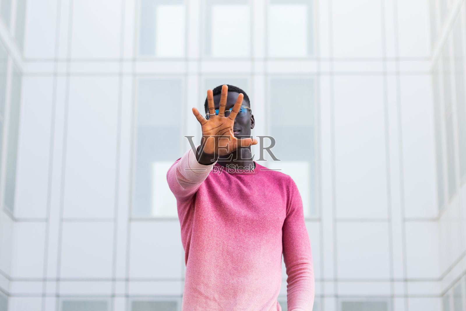黑人男子在城市街道上遮住脸并做出停止手势照片摄影图片