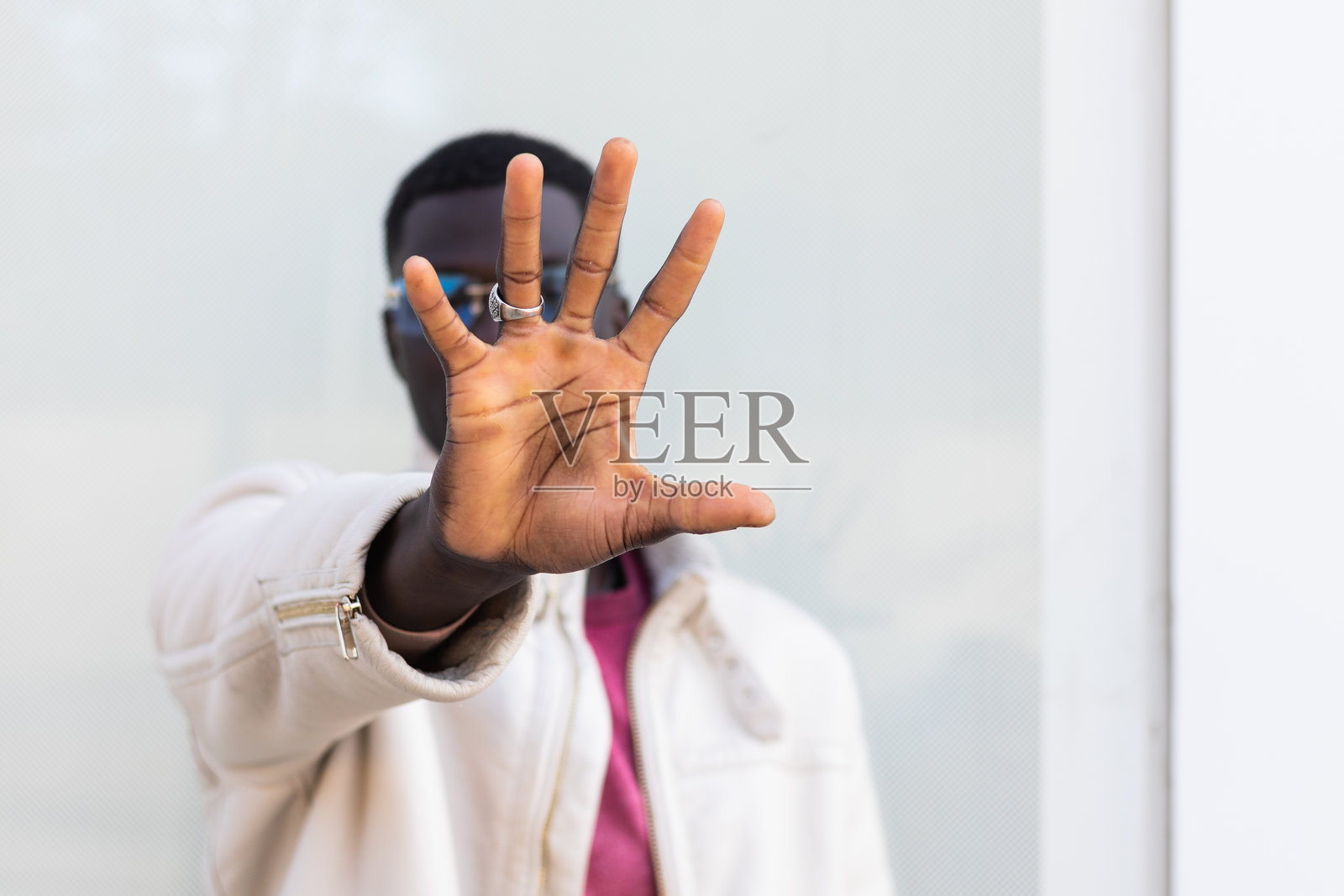 黑人男子在城市街道上遮住脸并做出停止手势照片摄影图片