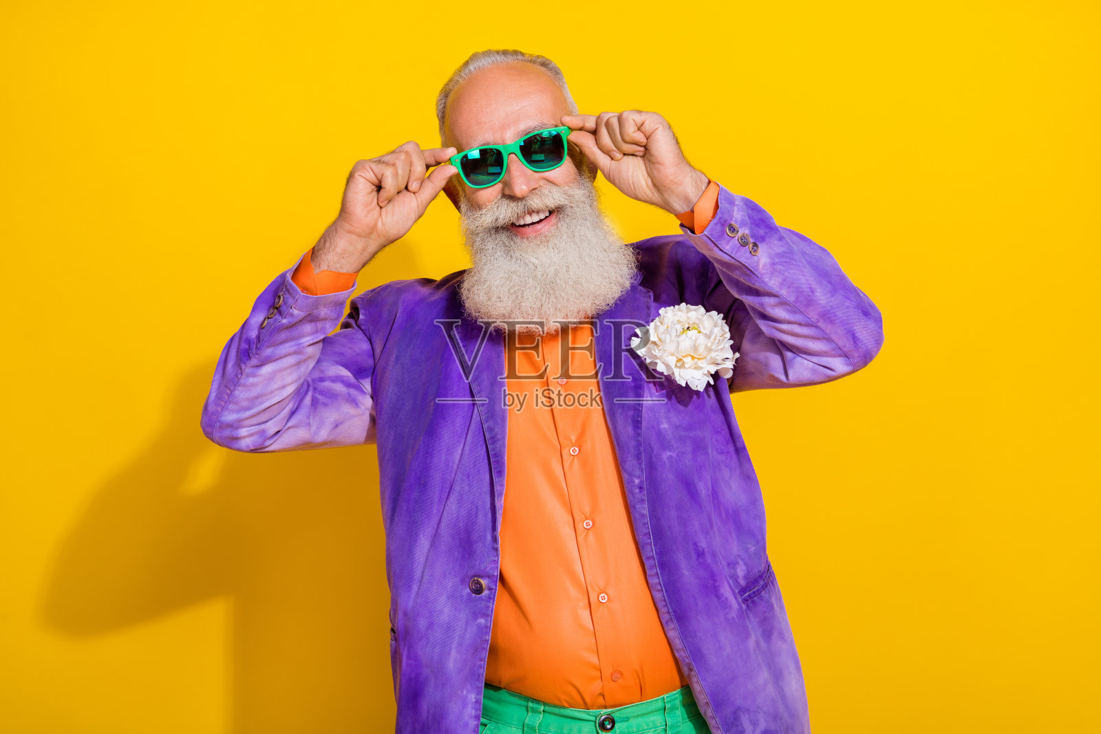 快乐迷人的老年男士，身穿80年代风格的时尚服装，参加校友聚会，手握亮眼配饰，背景为黄色。照片摄影图片