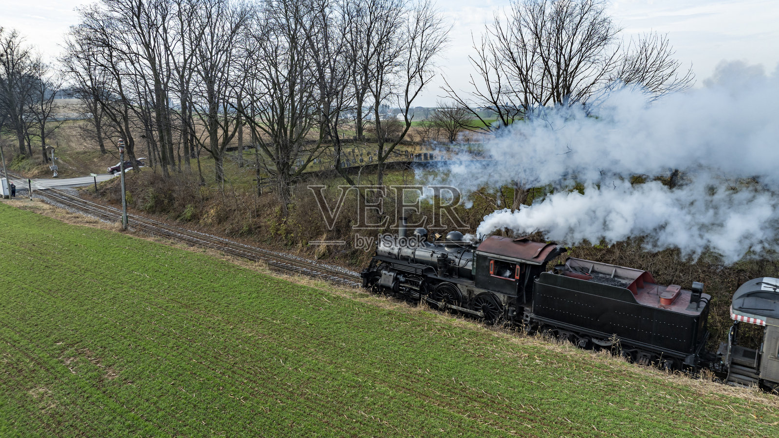 蒸汽火车在宁静的乡村风景中穿过早春的绿色田野照片摄影图片