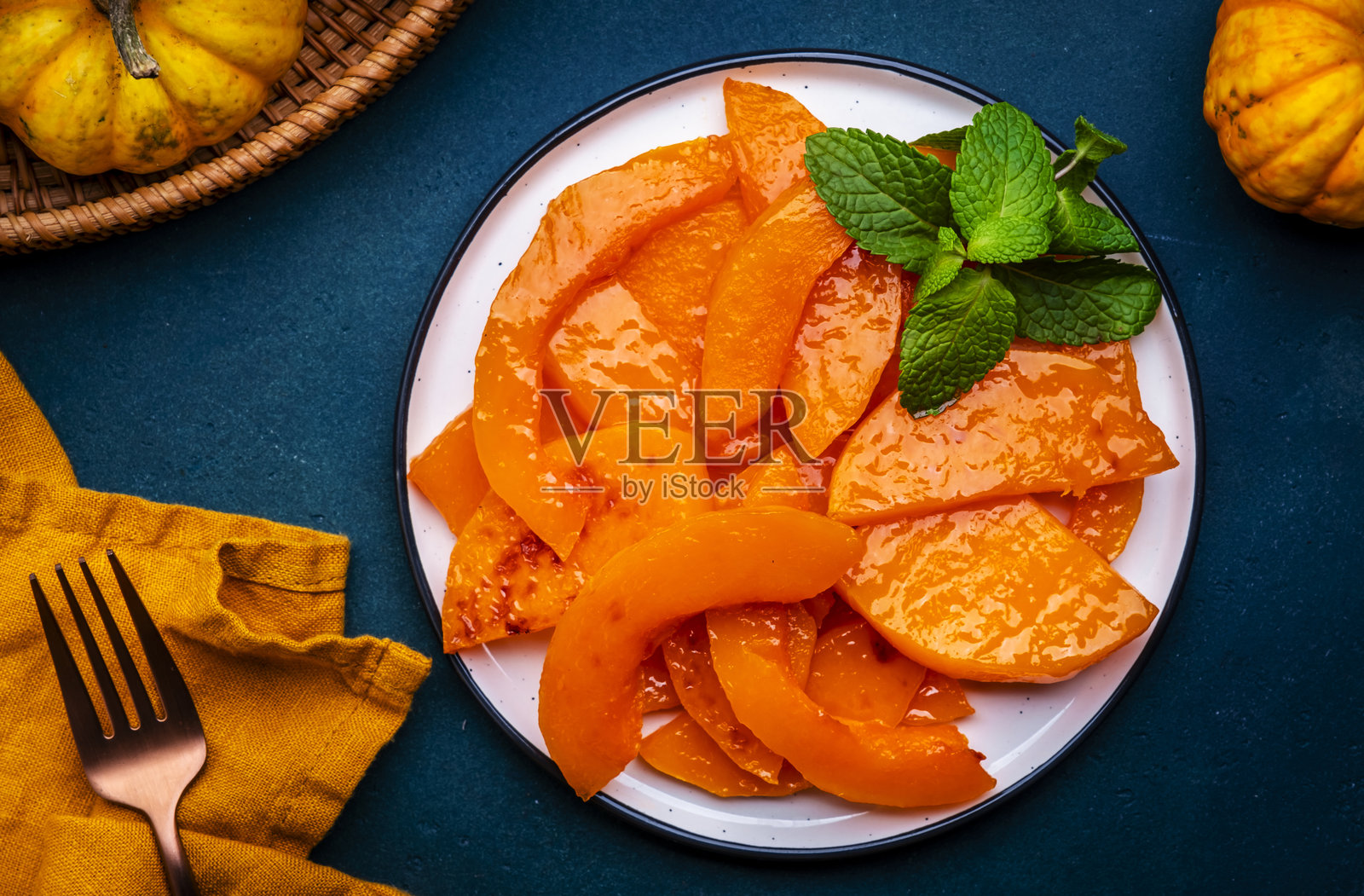 蓝色背景上的烤南瓜片，秋季健康甜点。俯视图照片摄影图片