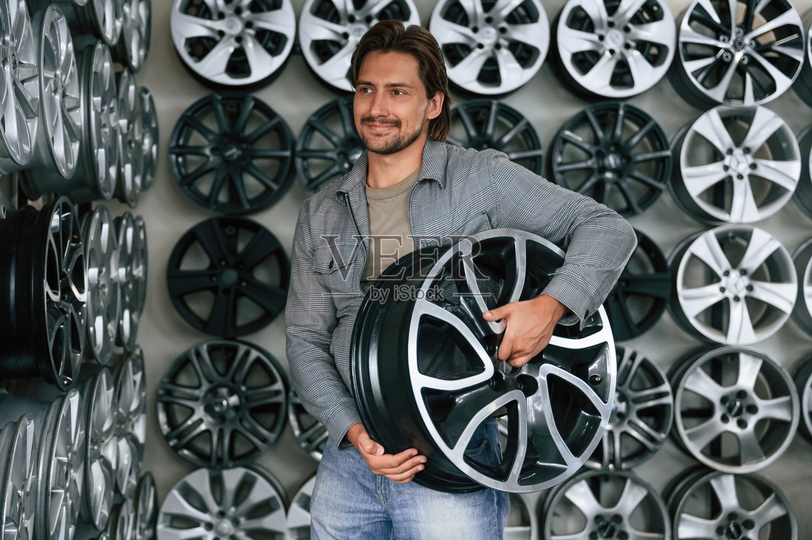 墙上有许多圆盘。一个人在轮胎安装汽车服务中。照片摄影图片