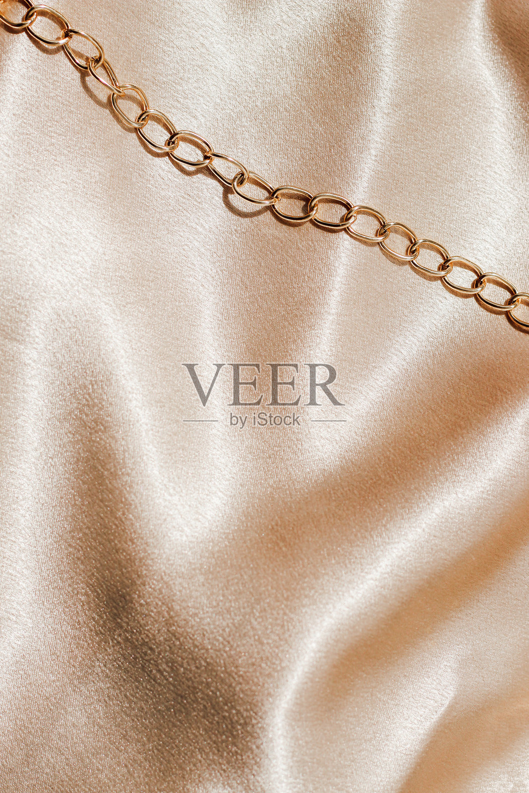 金色丝绸面料上的金链装饰，留有文本空间照片摄影图片