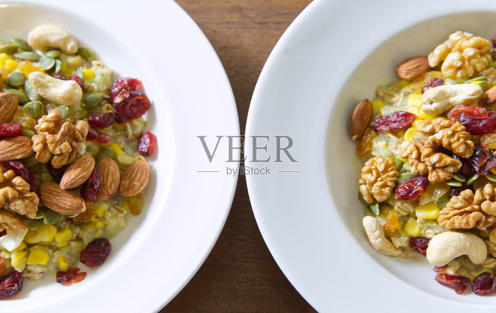 白盘中盛放着米粉或糯米粉与玉米混合，顶部撒有杏仁、腰果、核桃、蔓越莓和葡萄干。照片摄影图片