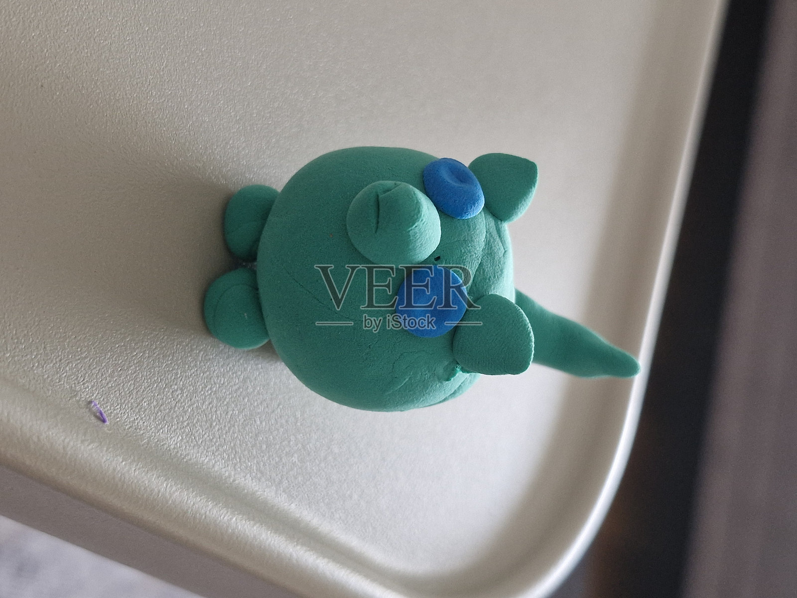 用粘土制作的小绿狗，拥有蓝色的眼睛。照片摄影图片