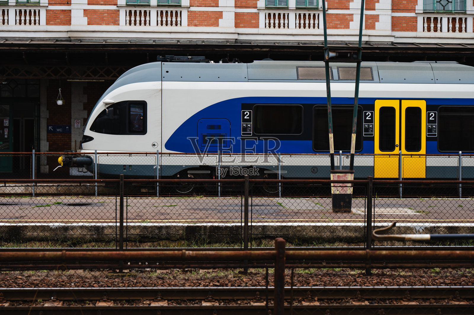 蓝白相间的客运列车停靠在火车站月台上照片摄影图片