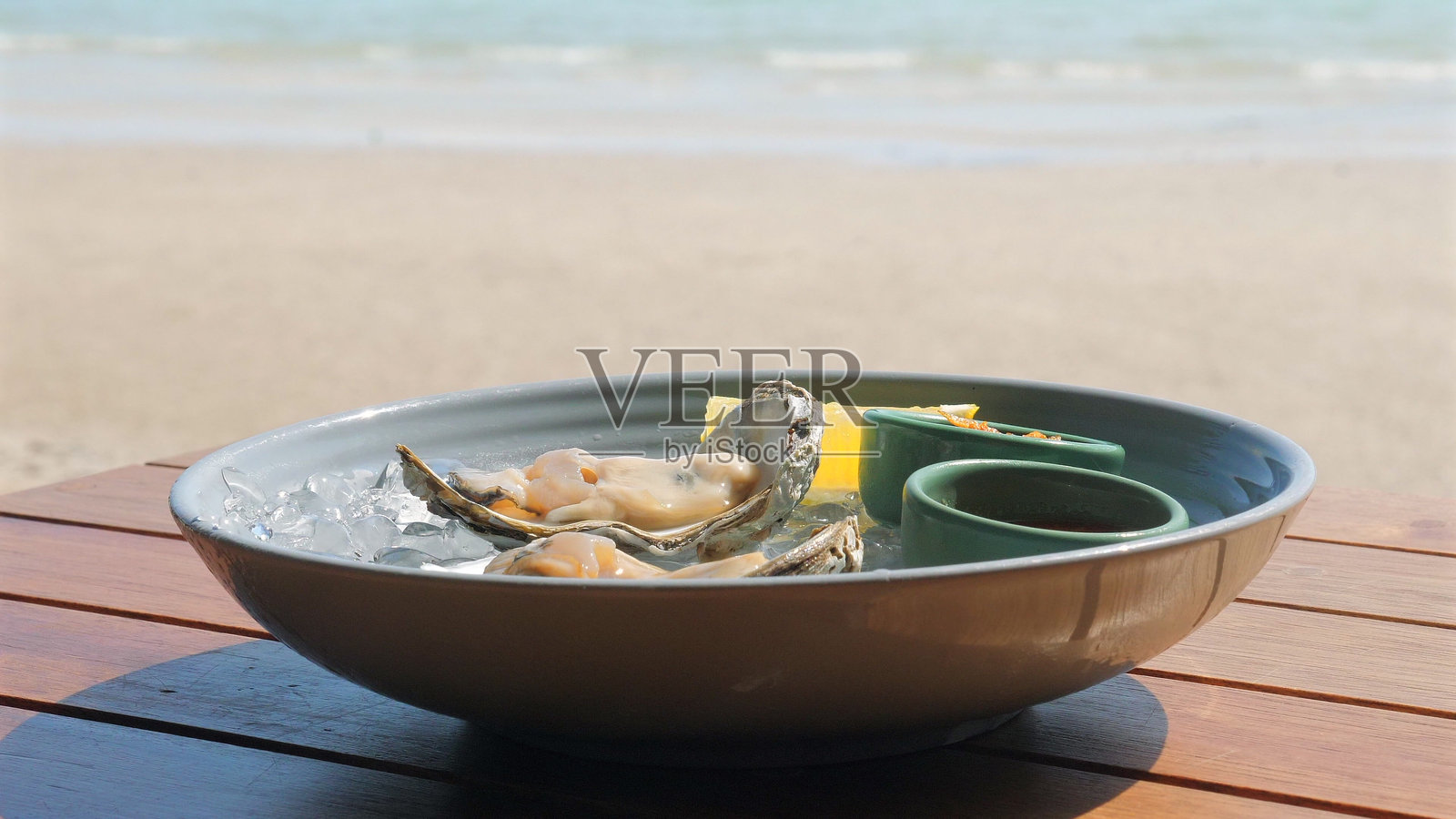 新鲜生蚝配冰块和调味酱，背景为美丽的风景照片摄影图片