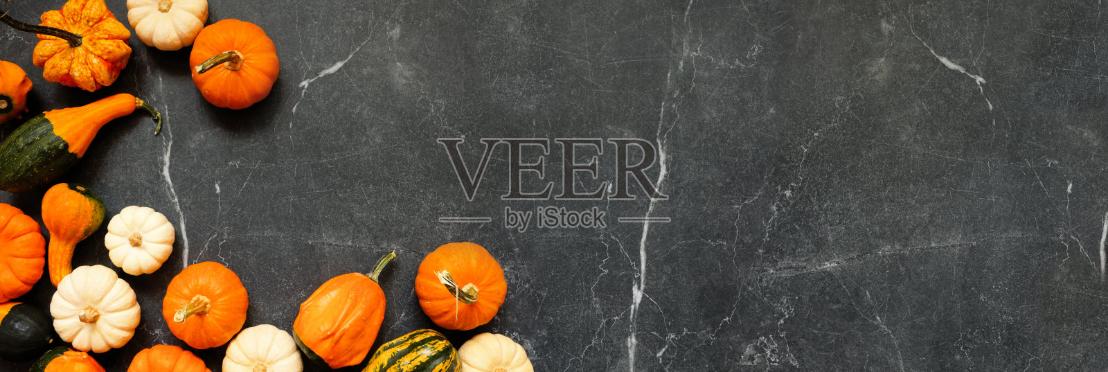 秋季南瓜和葫芦的角落边框。俯视图，背景为深色石材横幅，留有空白空间。照片摄影图片
