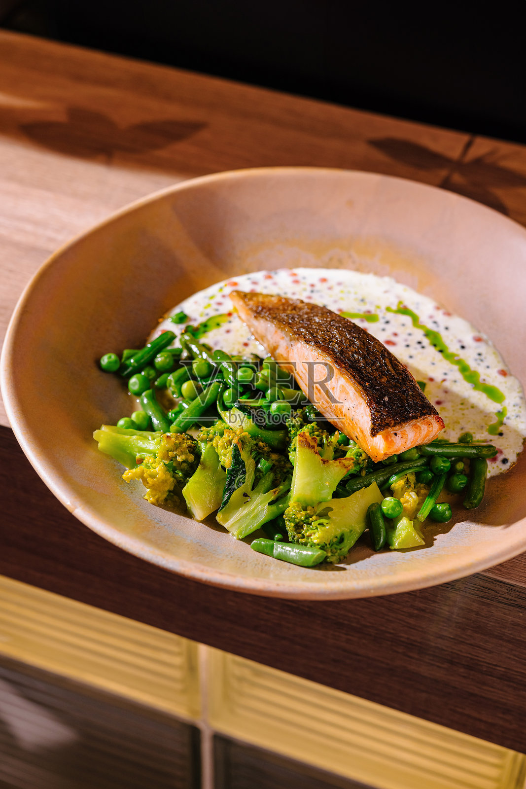 盘子上的三文鱼排配绿叶蔬菜和白色酱汁照片摄影图片