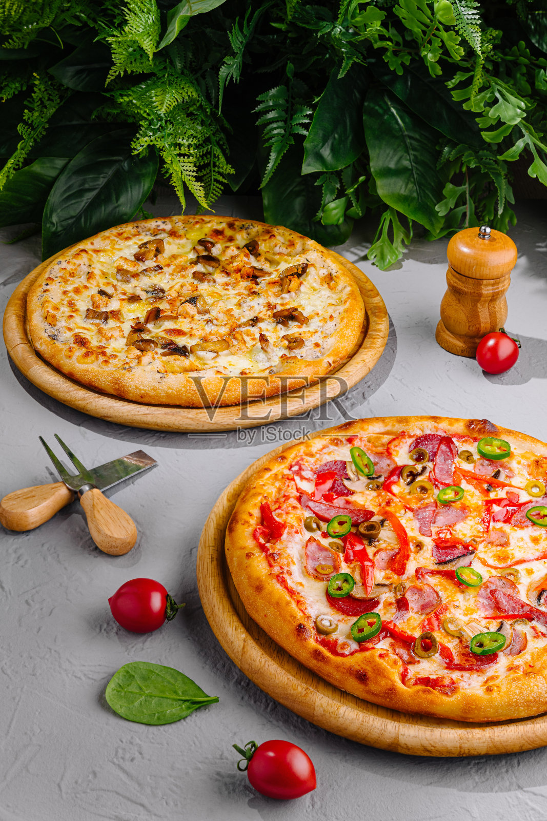 两款美味的披萨放在木托盘上，周围环绕着新鲜的食材照片摄影图片