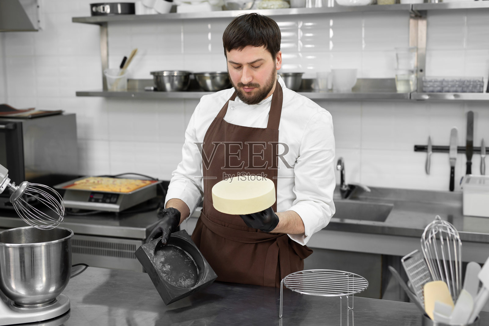 男糕点师从硅胶模具中取出冷冻慕斯蛋糕照片摄影图片