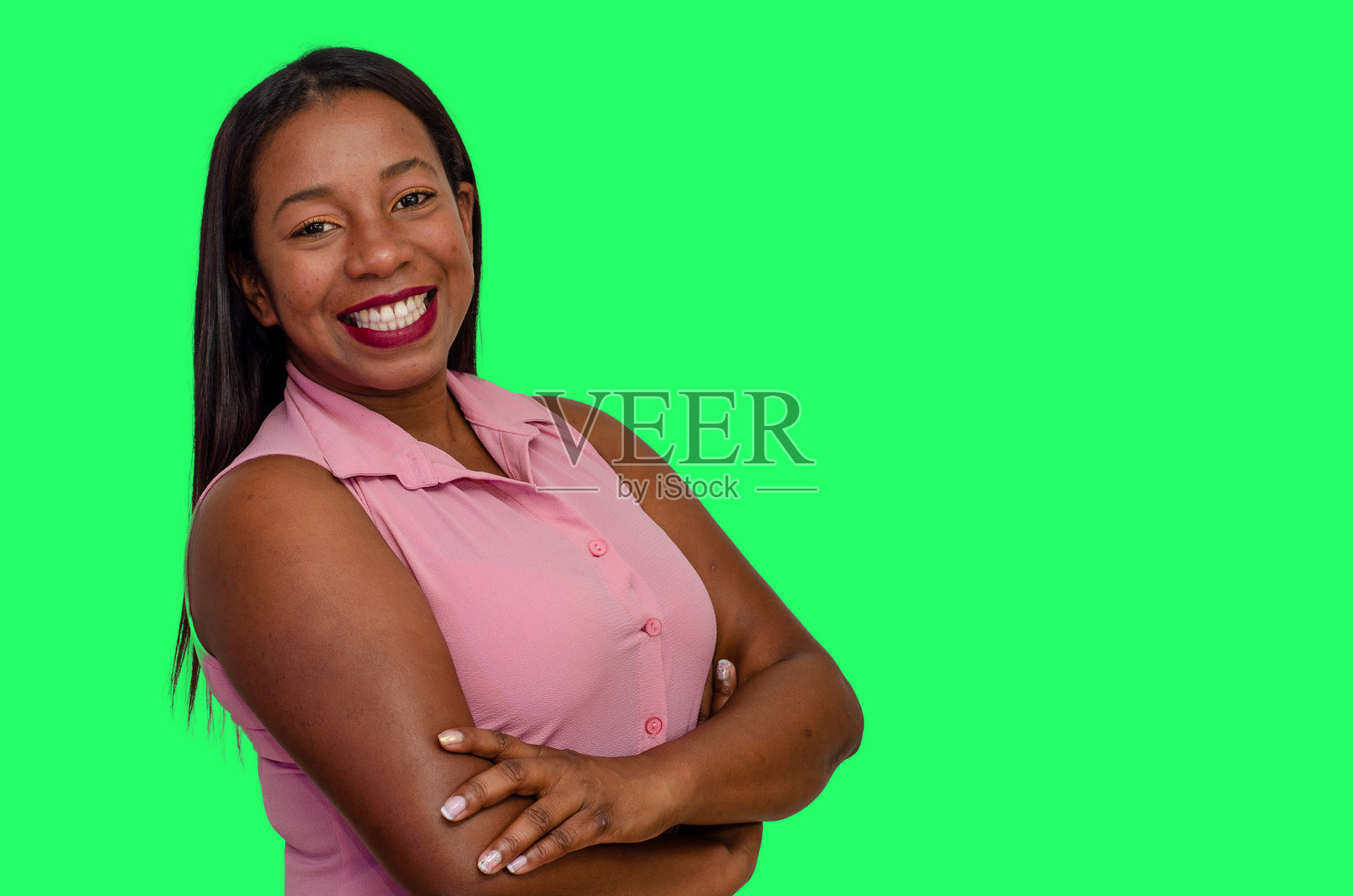 一位非裔美国女性，双臂交叉，长发披肩，穿着色彩丰富的休闲服，背景为绿色。照片摄影图片