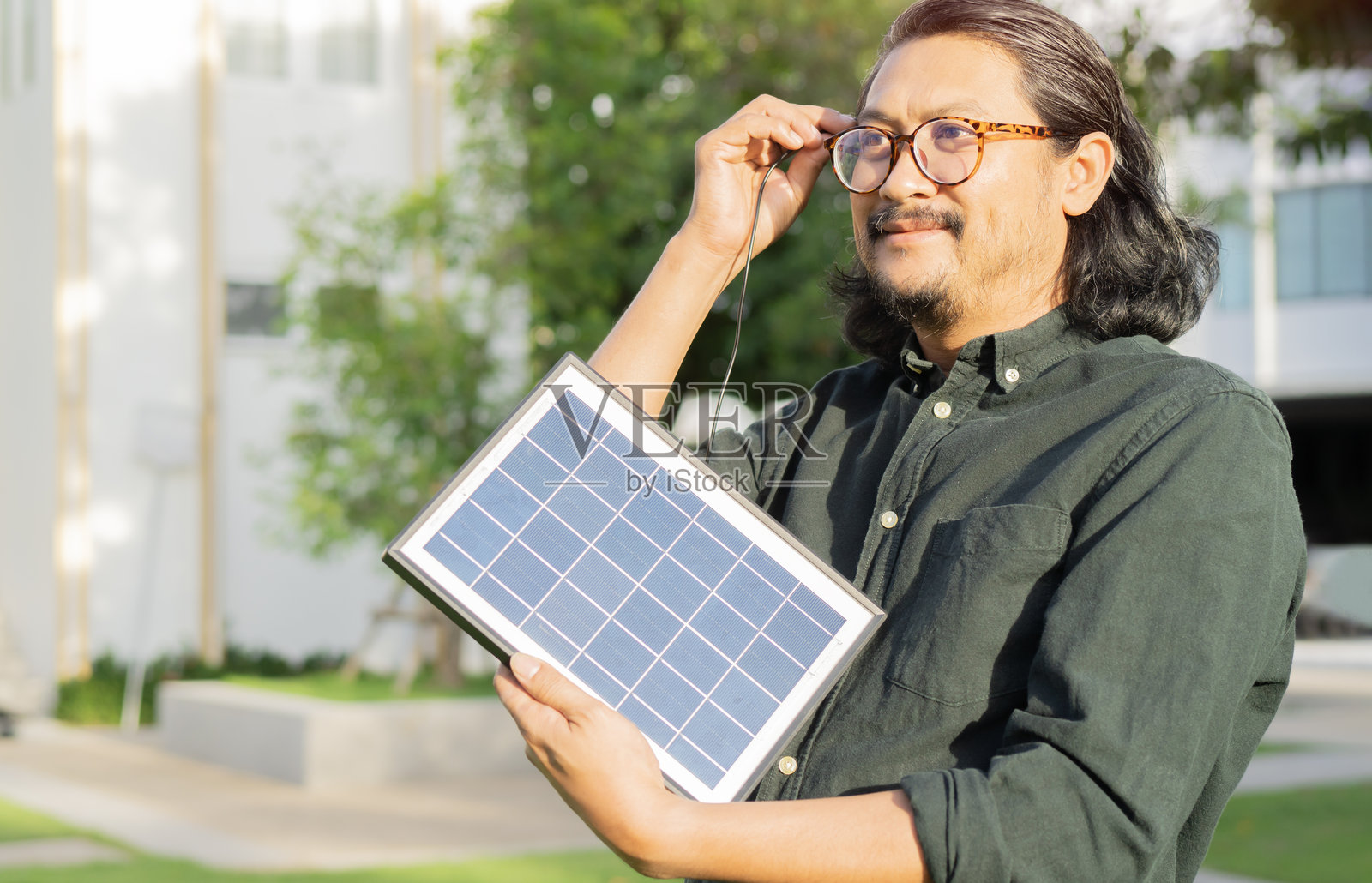 侧面特写镜头，活力四射的胡须男士正在通过便携式太阳能板充电。照片摄影图片