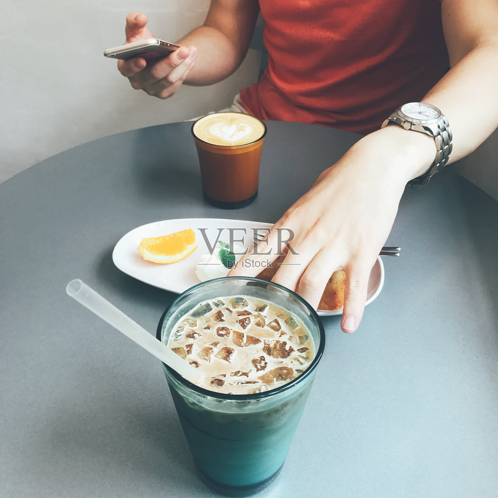 男人手持手机，喝着咖啡。橙子奶油磅蛋糕。照片摄影图片