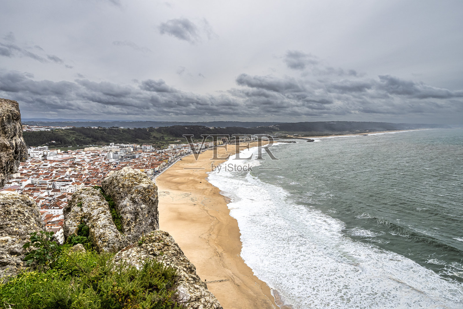 纳扎雷海滩，纳扎雷海岸，背景是葡萄牙纳扎雷镇的城市风景。照片摄影图片