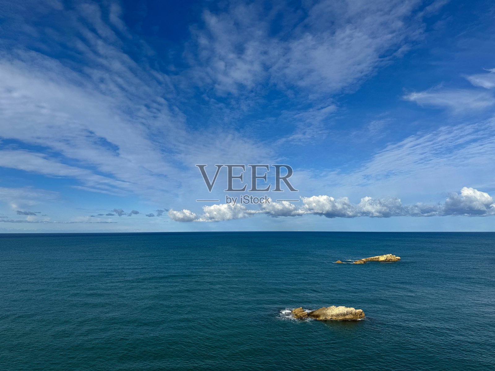 蓝色大海、岩石和美丽的云彩天空照片摄影图片