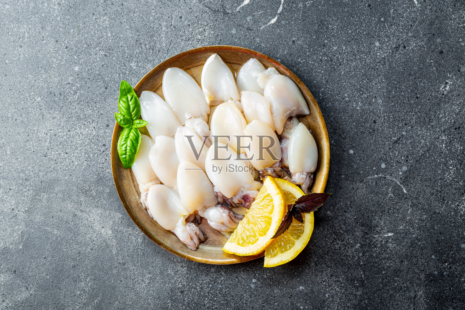 盘子上的生小墨鱼，配有大蒜、橄榄油和柠檬的俯视图照片摄影图片