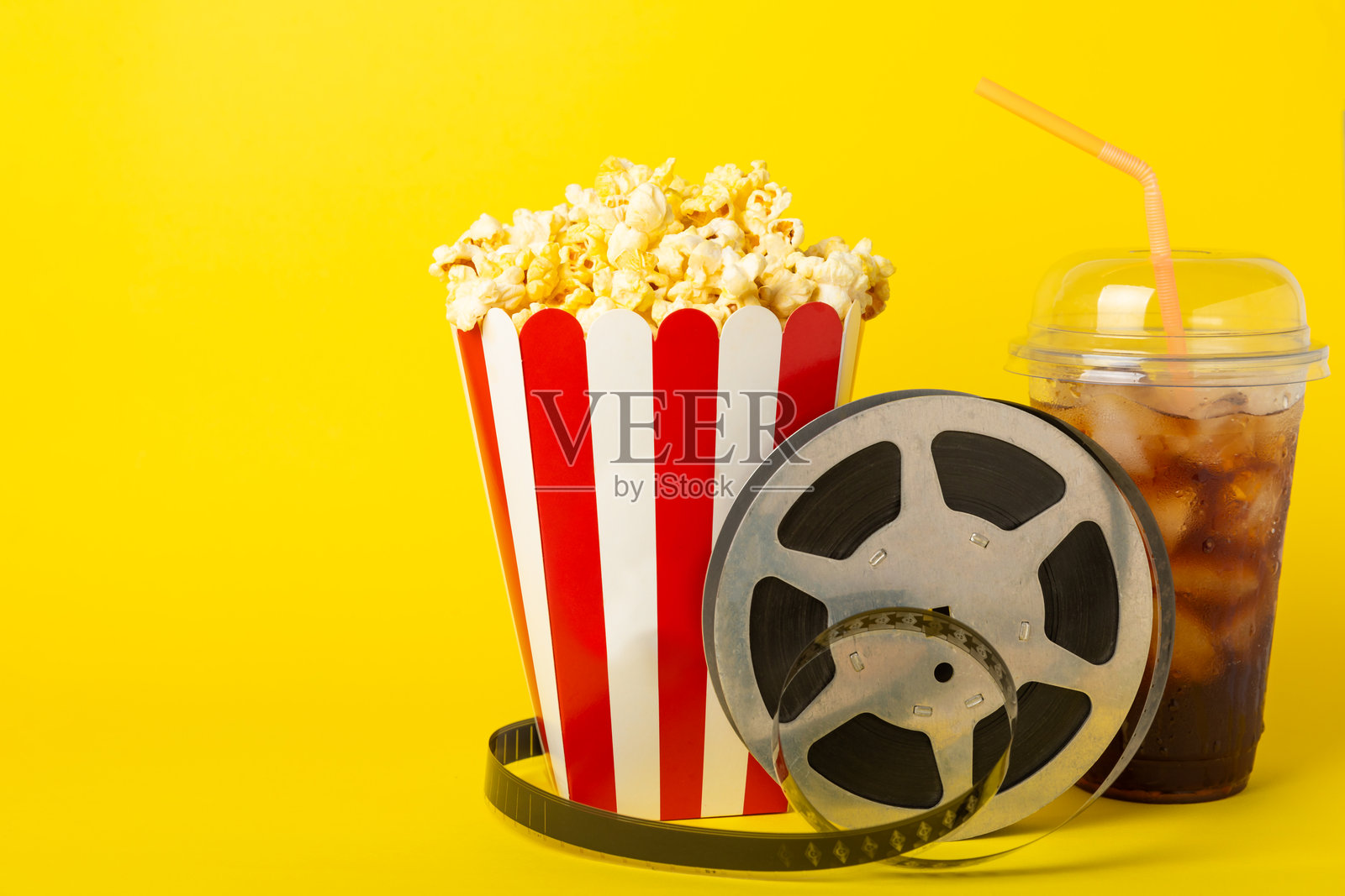 美味的爆米花装在桶里，旁边是冰凉的可乐饮料，还有电影票、电影拍板和3D眼镜，背景色彩鲜艳。电影院概念。观看电影。留白处。照片摄影图片