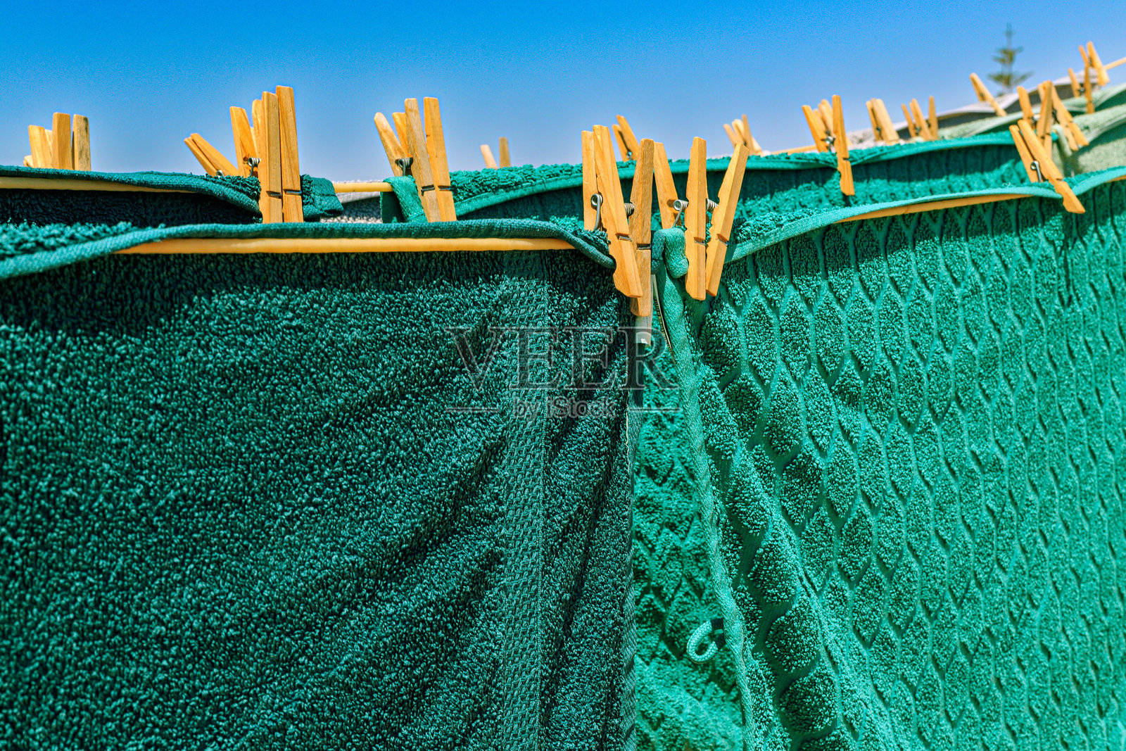 西班牙穆尔西亚 - 2024年7月25日 - 五彩斑斓的毛巾在阳光下晾干，映衬着晴朗的蓝天，营造出夏日的生动氛围照片摄影图片