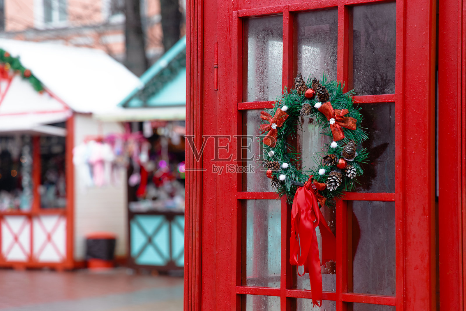 英格兰圣诞集市冬季十二月假日季节城市地标旅行，前景是经典的红色电话亭，上面装饰着花环。照片摄影图片