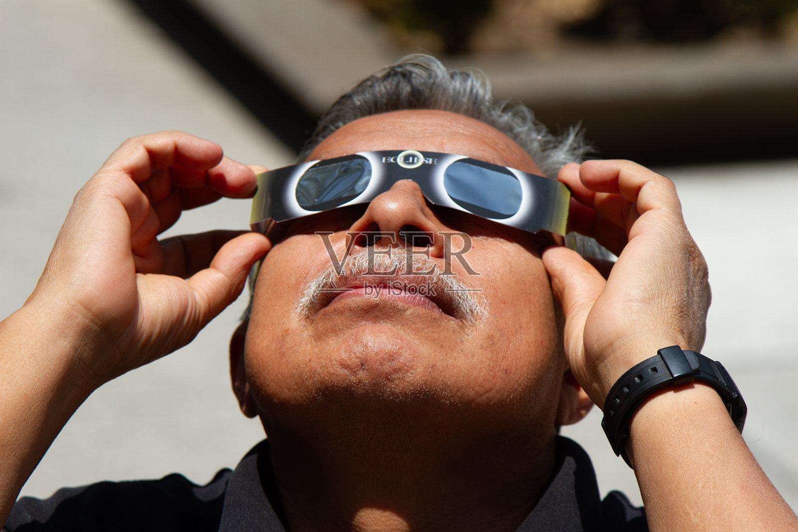 一个男人戴着特殊眼镜观看日全食。照片摄影图片