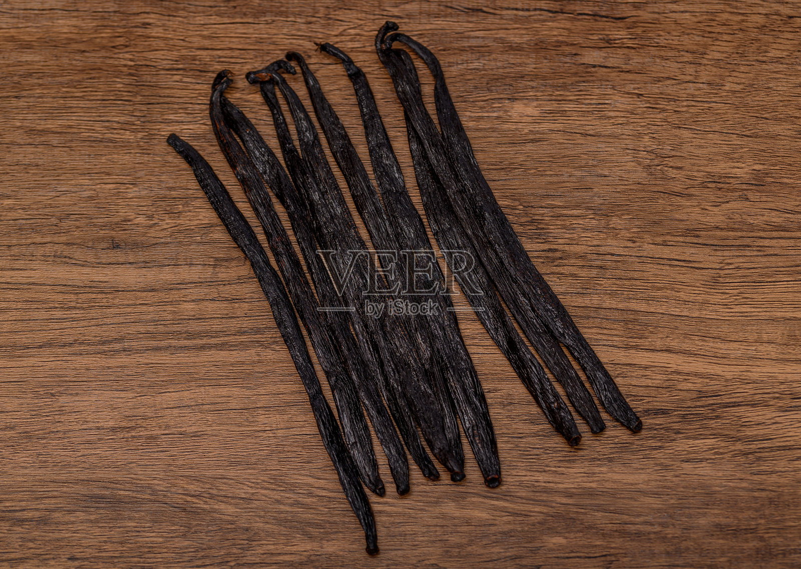 孤立的黑色厚波旁香草荚放在木桌上照片摄影图片