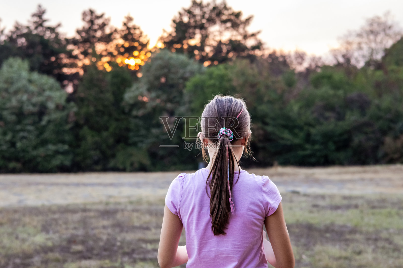 穿着粉色衬衫的美丽快乐女孩在公共公园里玩耍，长发飘逸。照片摄影图片