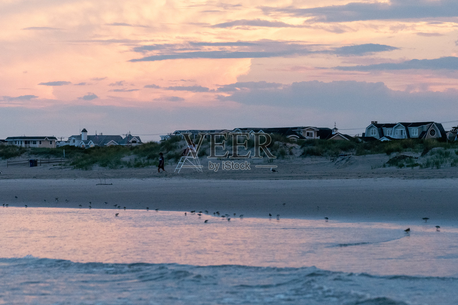 从海洋看向海岸线的房屋，夕阳下的戏剧性云彩。照片摄影图片